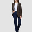 En kvinna klädd i en Women Serene Blazer Regular Walnut Herringbone över en vit t-shirt och mörkblå jeans.