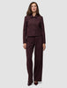En kvinna bär en kort jacka av modellen Women Serene i färgen Berry Pinstripe tillsammans med matchande byxor med vida ben i skandinavisk design.
