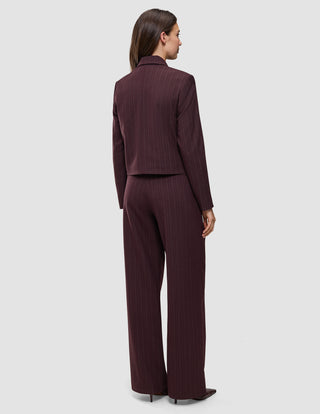 En kvinna sedd bakifrån, klädd i en kort jacka av modellen Women Serene Short Jacket Berry Pinstripe och matchande byxor med vida ben.
