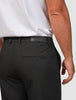 En man klädd i en vit t-shirt och svarta Essential Suit Pants Relaxed Fit med en läderlapp med märkeslogotyp i midjan.