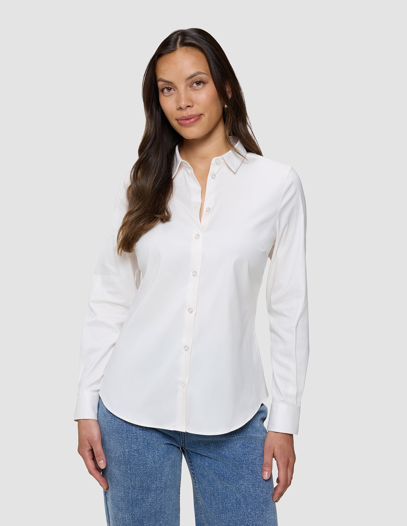 En kvinna klädd i en vit Oxford-skjorta i modellen White Orchid Slim för damer och blå jeans.