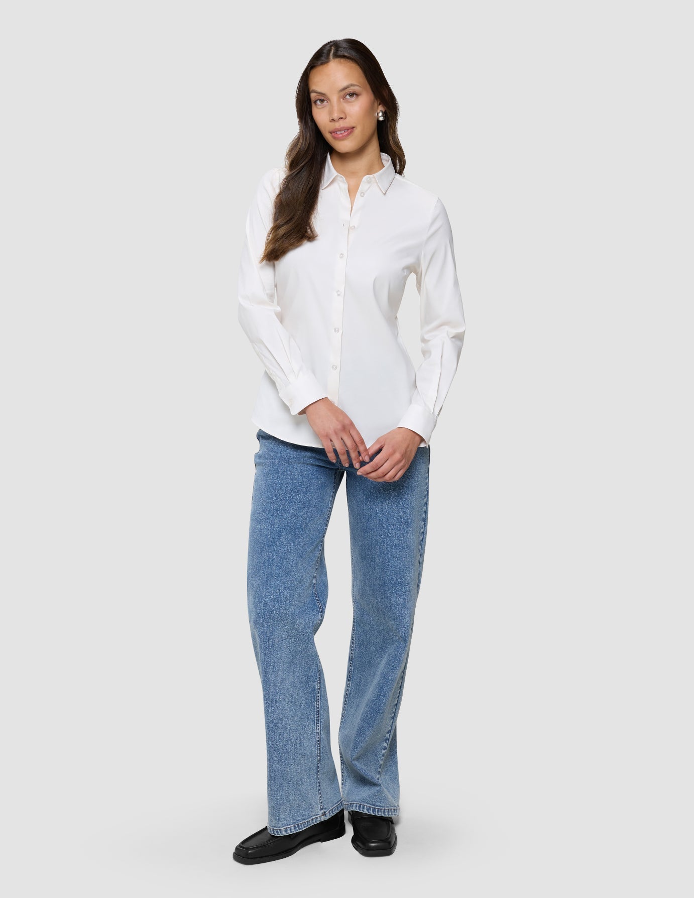 En kvinna klädd i en vit Oxford-skjorta i modellen White Orchid Slim och blå jeans.