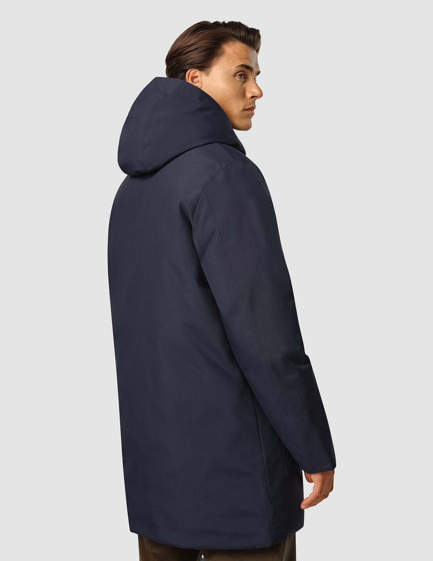 Sidoprofil av en person som bär en mörkblå funktionsjacka. Mörkblå funktionsjacka med huva, tillverkad av återvunnen polyester.