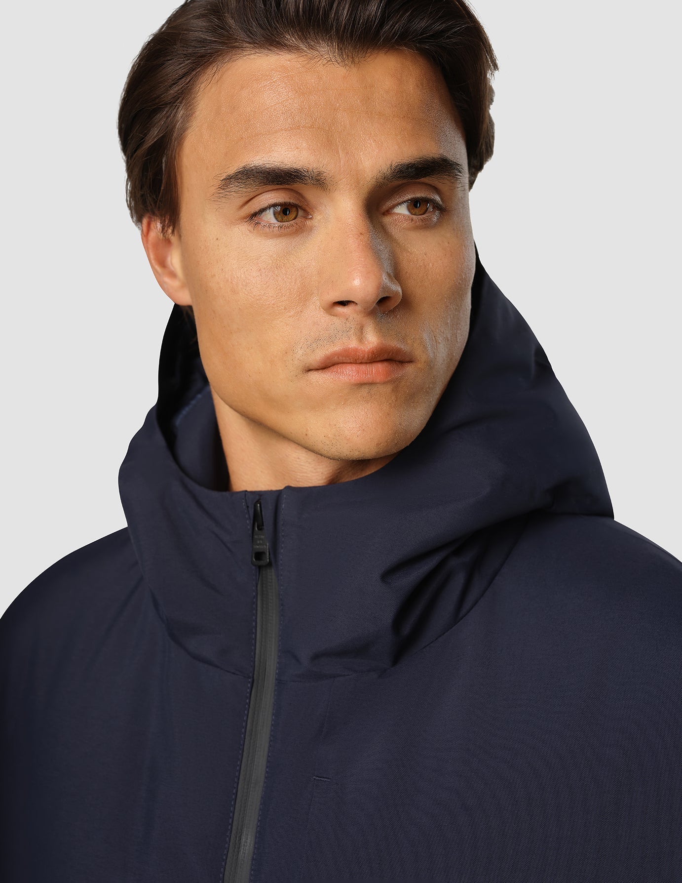En man klädd i en mörkblå Utility-jacka i återvunnen polyester med dragkedja framtill.