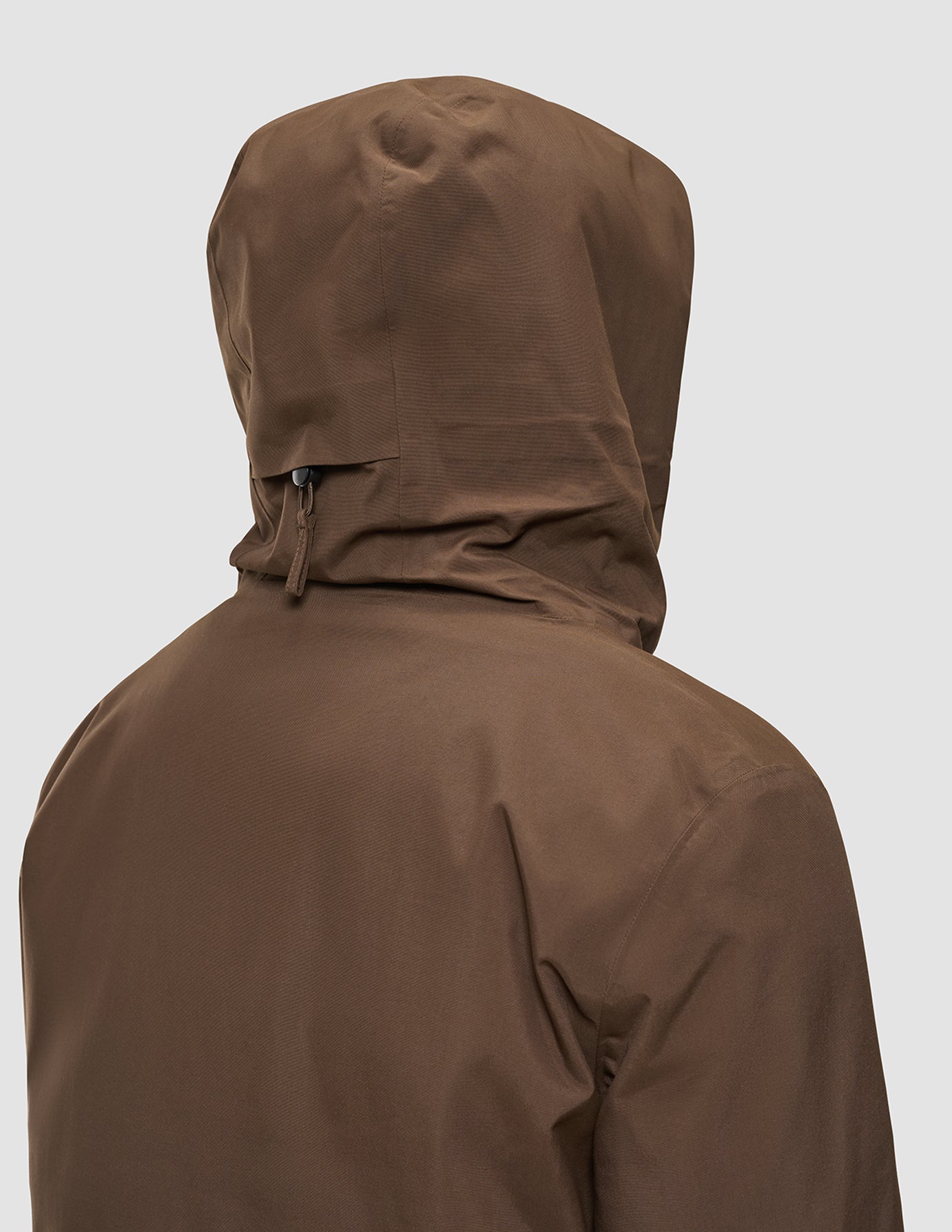 Bakifrånbild av en person som bär en brun Utility Jacket Saddle Brown som är vind- och vattentät.