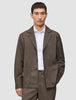 En man bär en brun, rutig Atelier Overshirt Dark Beige över en vit skjorta med knappar.