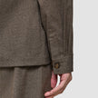 Närbild på en långärmad övertröja från Atelier i mörkbeige, med manschetter i bruten twill och en enda knapp.