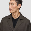 En man klädd i en mörkbrun Atelier Overshirt i brutet twill över en svart tröja.