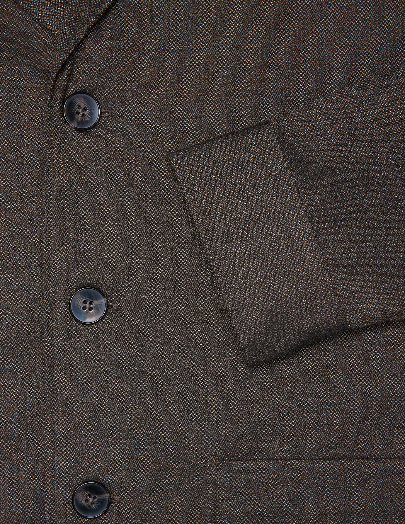 Närbild på Atelier Overshirt Dark Brown, med en mörkbrun, strukturerad väv i bruten twill och tre mörka knappar.