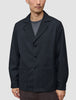 En person som bär en Atelier Overshirt Dark Navy i bruten twill med skårade kragar och två påsydda fickor.