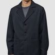 En person som bär en Atelier Overshirt Dark Navy i bruten twill med skårade kragar och två påsydda fickor.