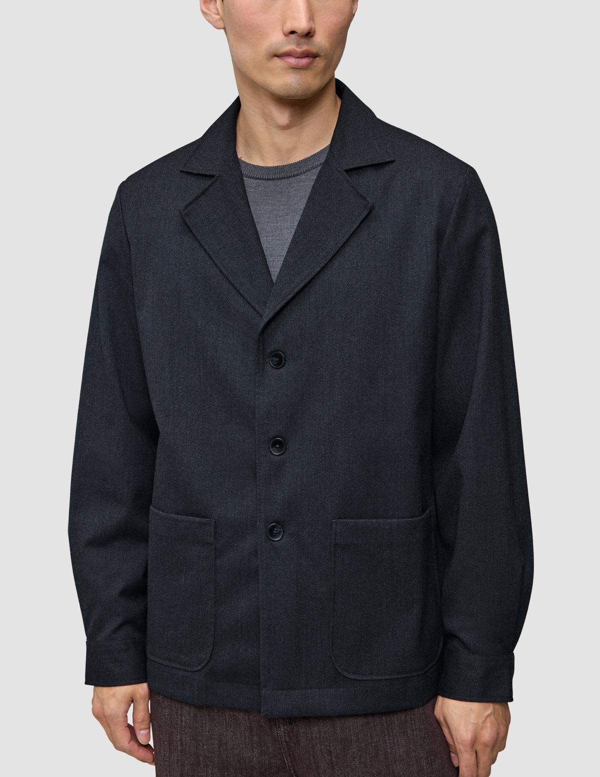 En person som bär en Atelier Overshirt Dark Navy i bruten twill med skårade kragar och två påsydda fickor.