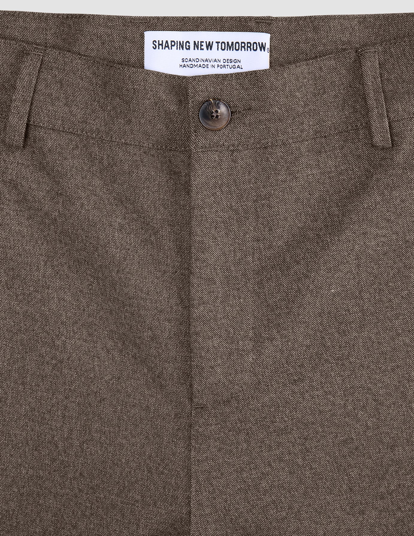 Närbild på midjebandet, knappen och mittsömmen på byxorna Atelier Pants Relaxed Dark Beige i bruten twill.