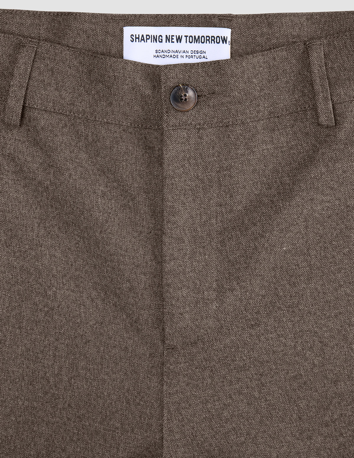 Närbild på midjebandet, knappen och mittsömmen på byxorna Atelier Pants Relaxed Dark Beige i bruten twill.