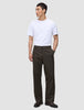 En person i en vit t-shirt, byxor av modellen Atelier Pants Relaxed i mörkbrunt och mörka läderskor.