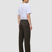 En man sedd bakifrån, klädd i en vit t-shirt och mörkbruna Atelier Pants Relaxed.