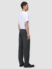 En person i profil bär en vit t-shirt och ett par Atelier Pants Relaxed i mörkgrått med avslappnad passform.