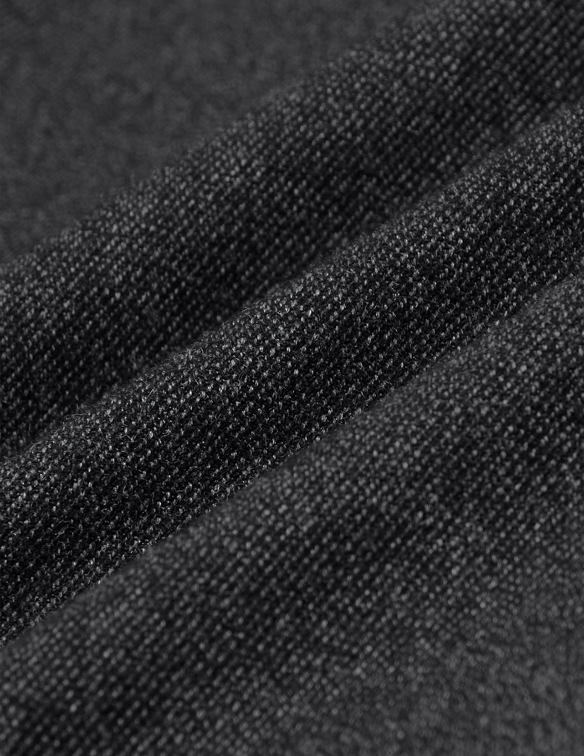 Närbild på mörkgråa byxor i bruten twill från Atelier Pants Relaxed Dark Grey, i ett tyg med strukturerat stickmönster.