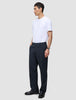 En man klädd i en vit t-shirt och byxor av modellen Atelier Pants Relaxed Dark Navy i bruten twill.