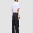 En person sedd bakifrån, klädd i en vit t-shirt och byxor av modellen Atelier Pants Relaxed Dark Navy.