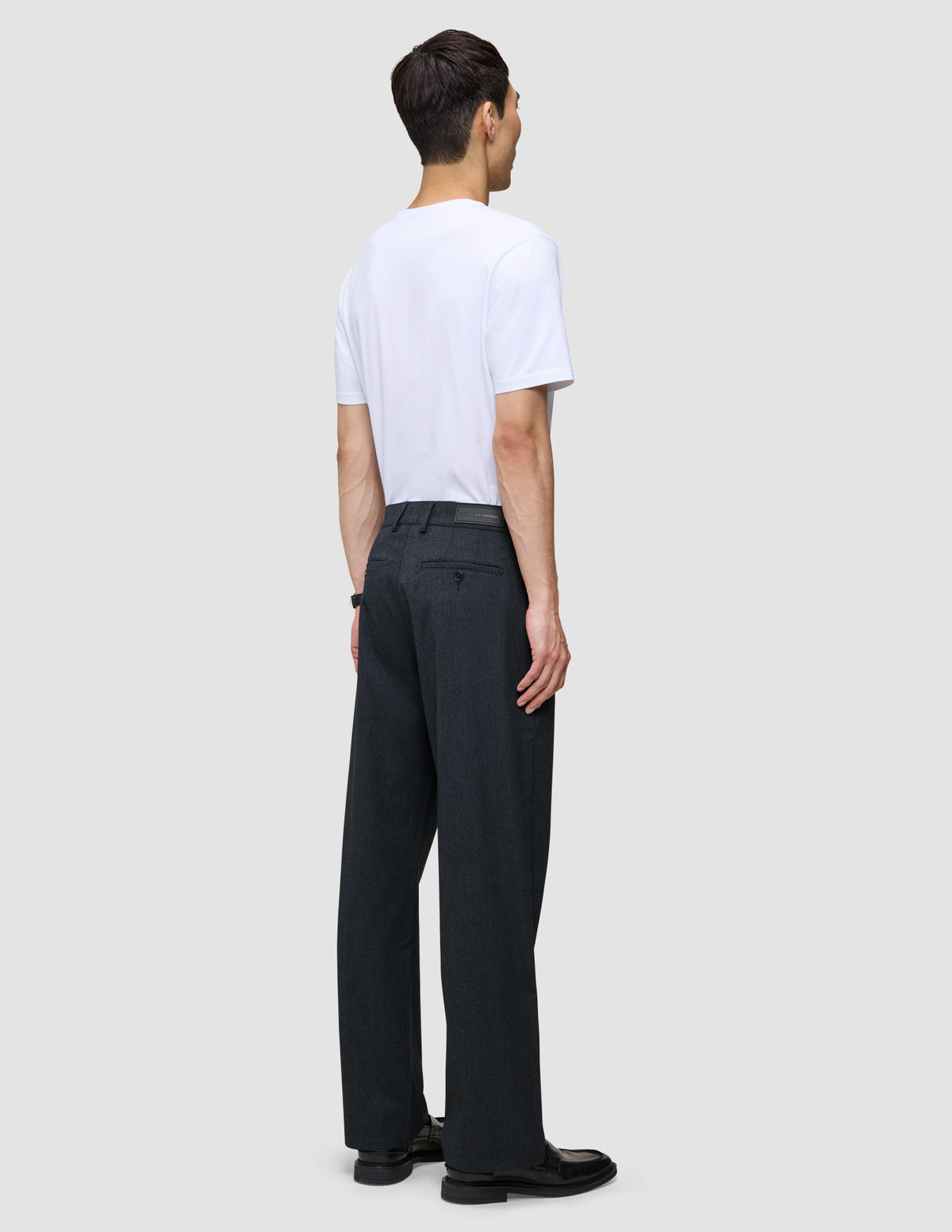 En person sedd bakifrån, klädd i en vit t-shirt och byxor av modellen Atelier Pants Relaxed Dark Navy.