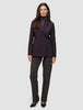 En kvinna klädd i en mörklila Women’s Avira Blazer Burgundy Berry över en grå polotröja och mörka byxor.