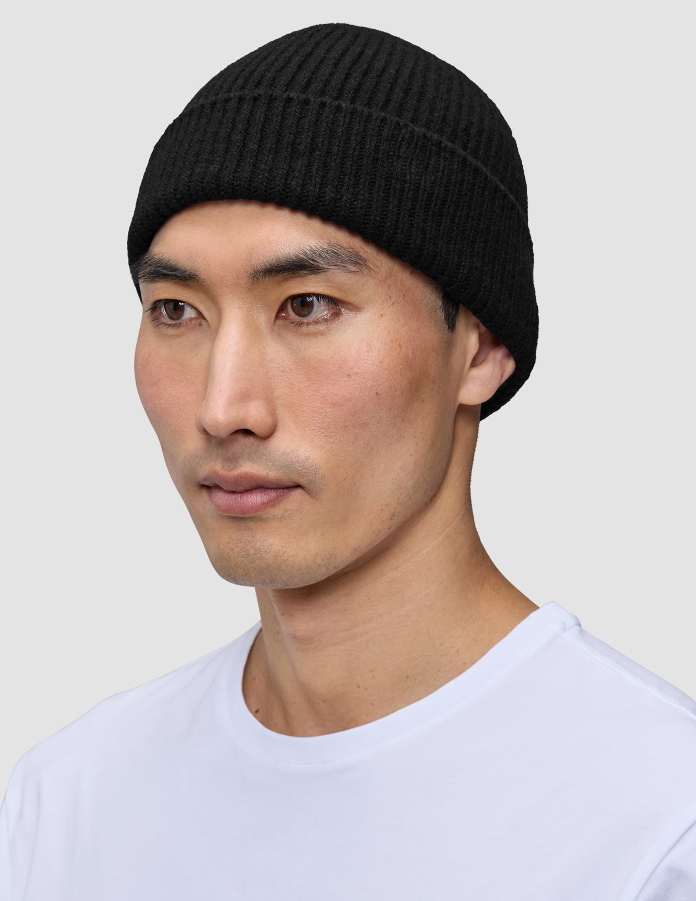 En man som bär en svart, ribbstickad mössa, Beanie Black.