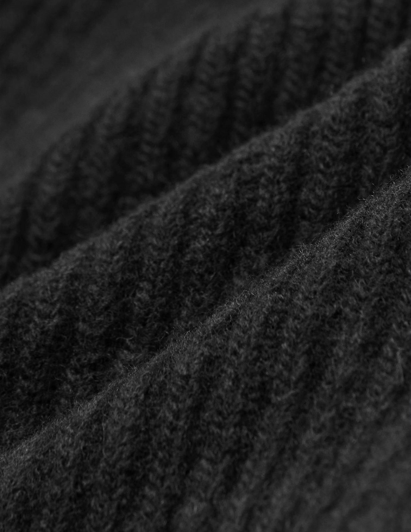 Närbild på det svarta, ribbade stickade tyget av merinoull på en Beanie Black.