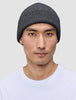 En person som bär en varm, mörkgrå, ribbad mössa i merinoull, modell Beanie Dark Grey.
