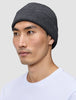 En person som bär en varm, mörkgrå, ribbad mössa i merinoull, modell Beanie Dark Grey.