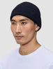 En person som bär en Wool Beanie Navy, en mörkblå ribbad mössa med klassisk skandinavisk design.