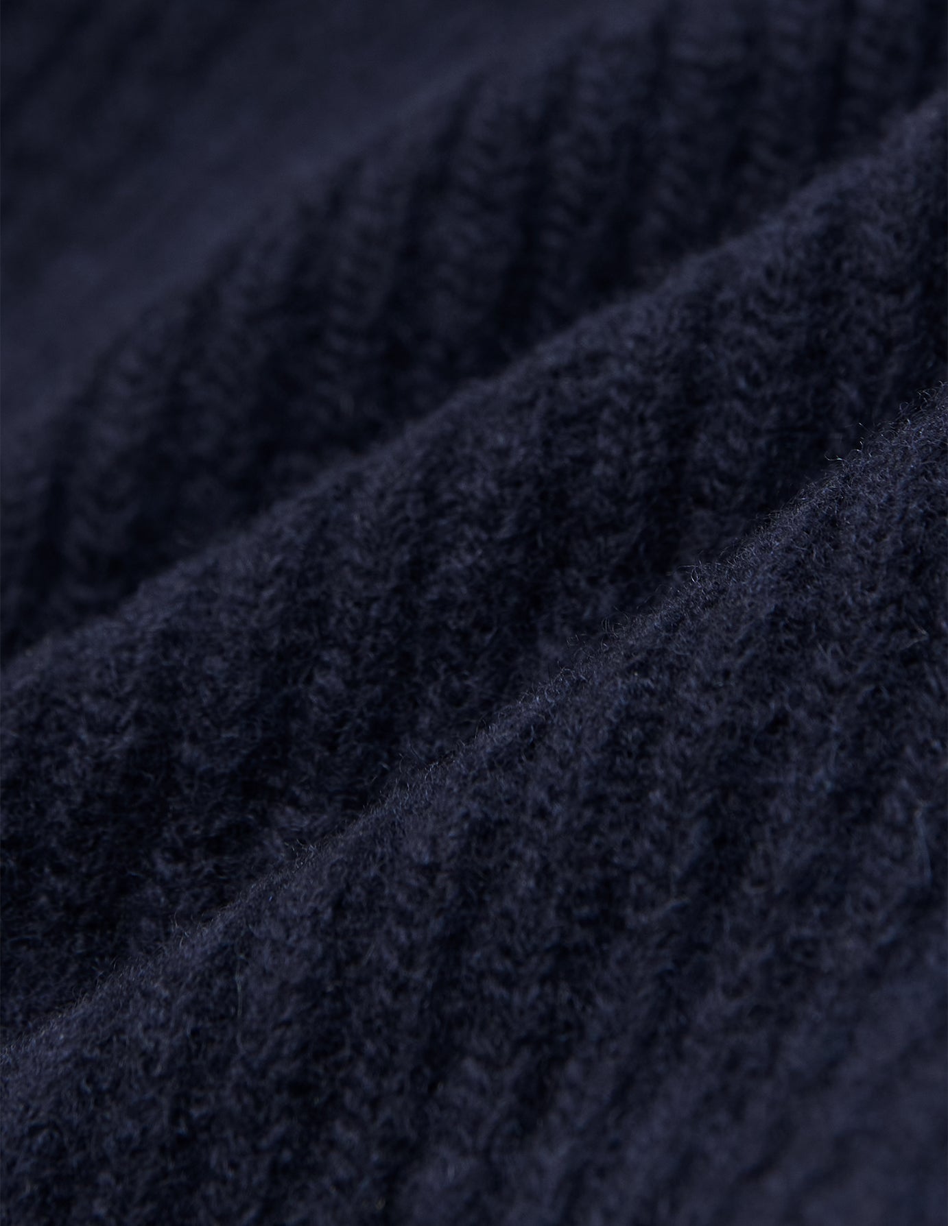 Närbild på en marinblå, ribbad stickad ullmössa (Wool Beanie Navy).