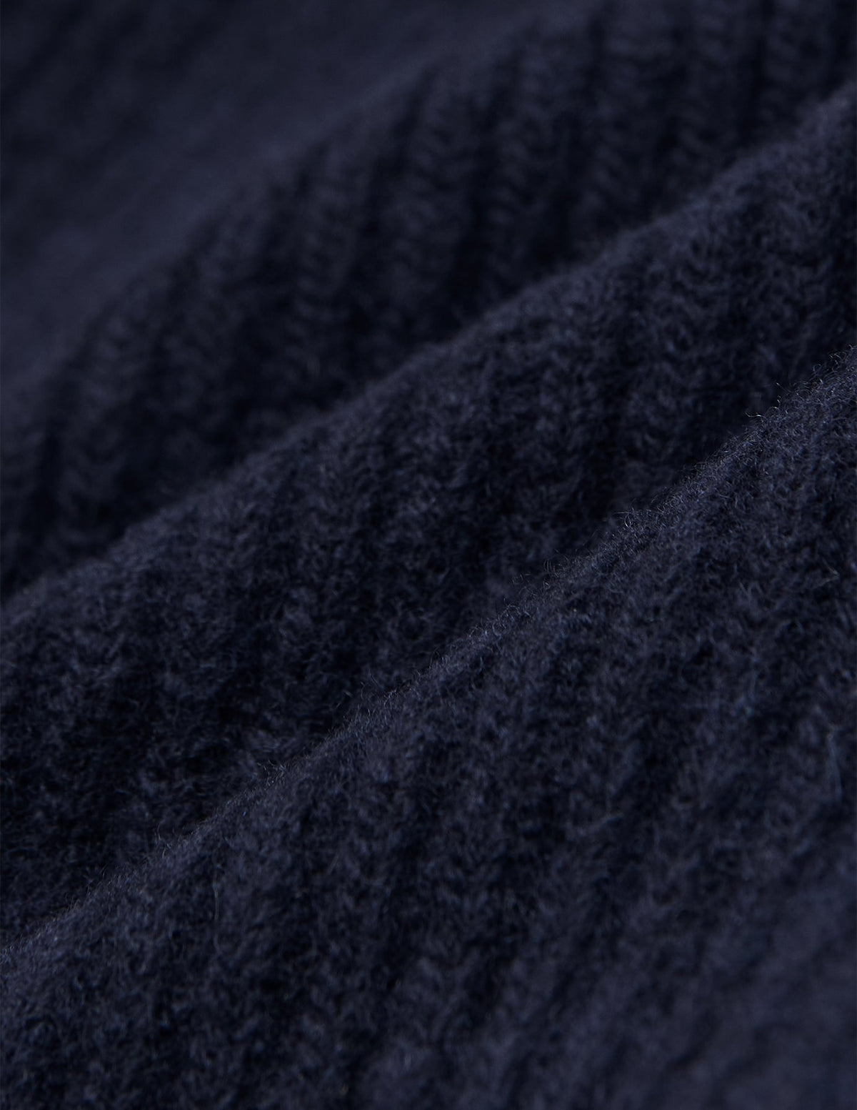 Närbild på en marinblå, ribbad stickad ullmössa (Wool Beanie Navy).