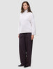 En kvinna klädd i en damtröja av typen Chunky Soft Wool Knit Turtleneck Sugar Melange och mörka byxor med vida ben.