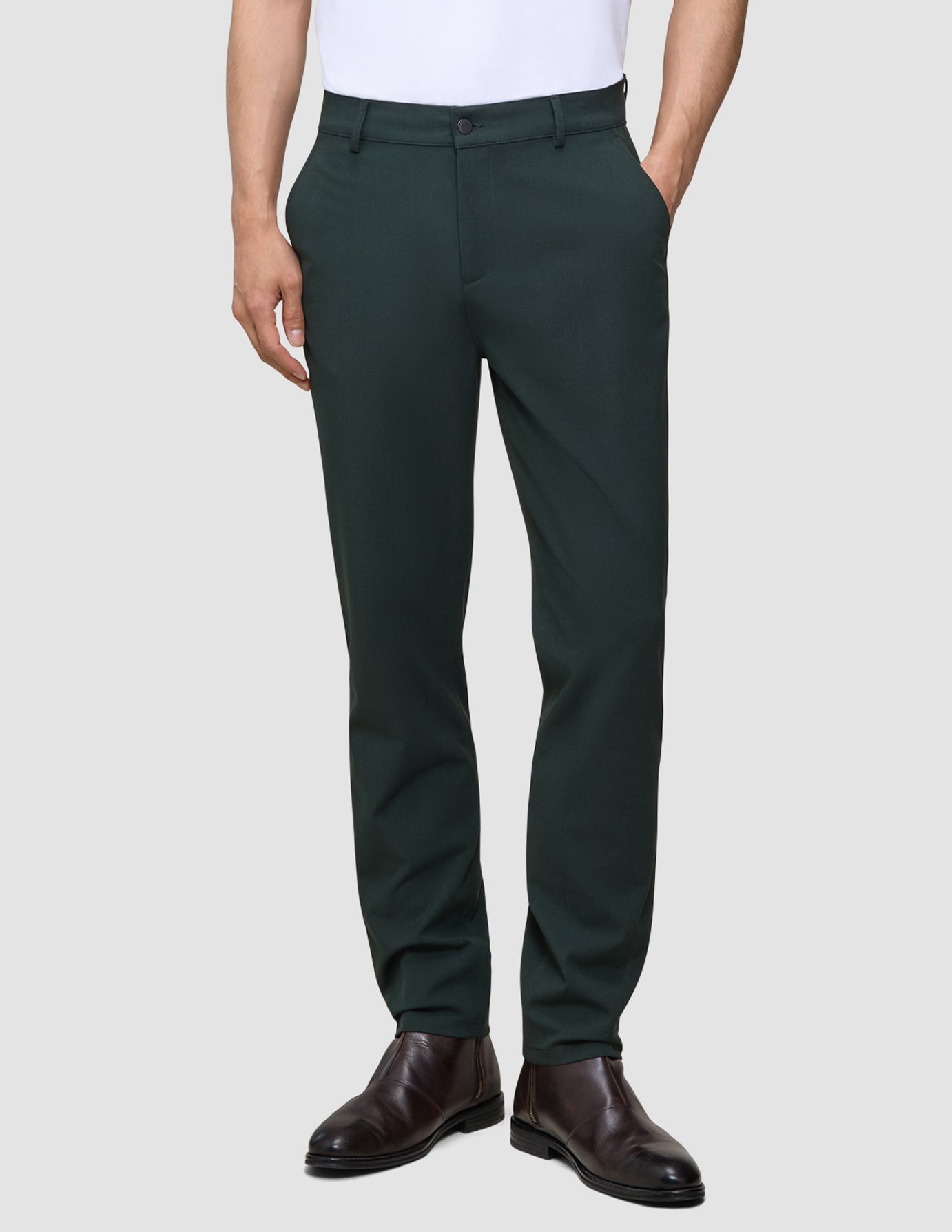 En person som bär mörkgröna Ease Pants Regular Northern Pine och bruna läderstövlar.