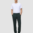 En man i en vit t-shirt och Ease Pants Regular Northern Pine med händerna i fickorna.
