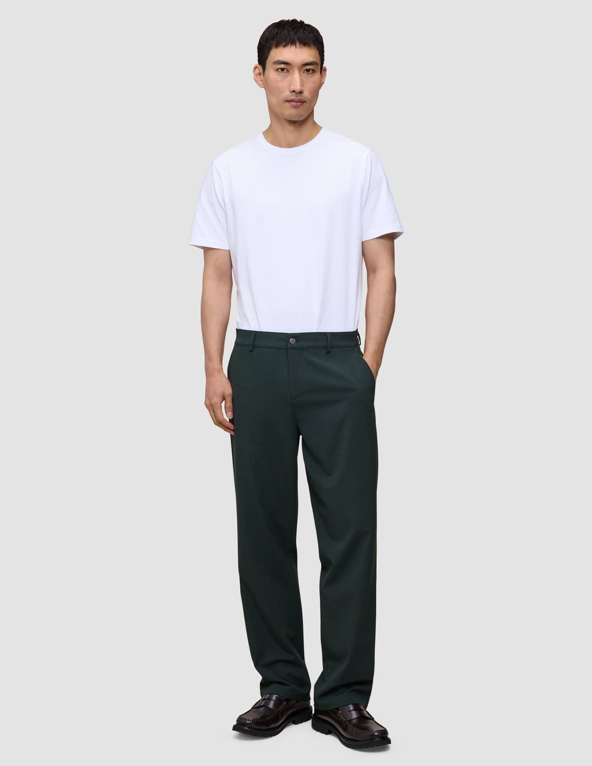En person klädd i en vit t-shirt, mörka loafers och Ease Pants Relaxed Fit Northern Pine.
