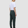 En person klädd i en vit t-shirt, Ease Pants Slim Northern Pine och bruna läderstövlar.