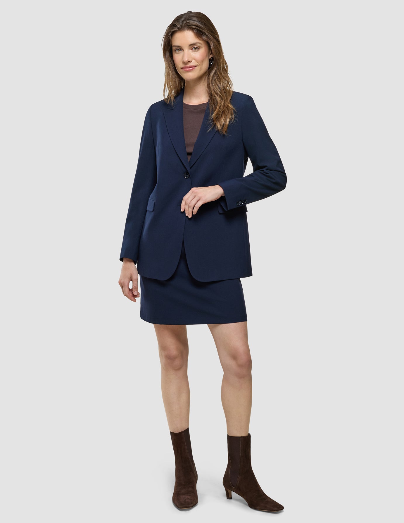En kvinna i en mörkblå kavaj och en kort kjol från Women Ease, modell ”Blue Nights”, samt bruna stövlar.