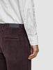 En person som bär en Elevated Shirt Regular i ljusgrå randigt och mörklila corduroybyxor.