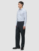 En man bär en blå randig skjorta av modellen Elevated Shirt Slim Classic och kolgrå byxor medan han står i profil.
