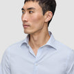 En man klädd i en Elevated Shirt Slim Classic Blue Striped – en smalpassad, ljusblå och vitrandig skjorta med knappar.