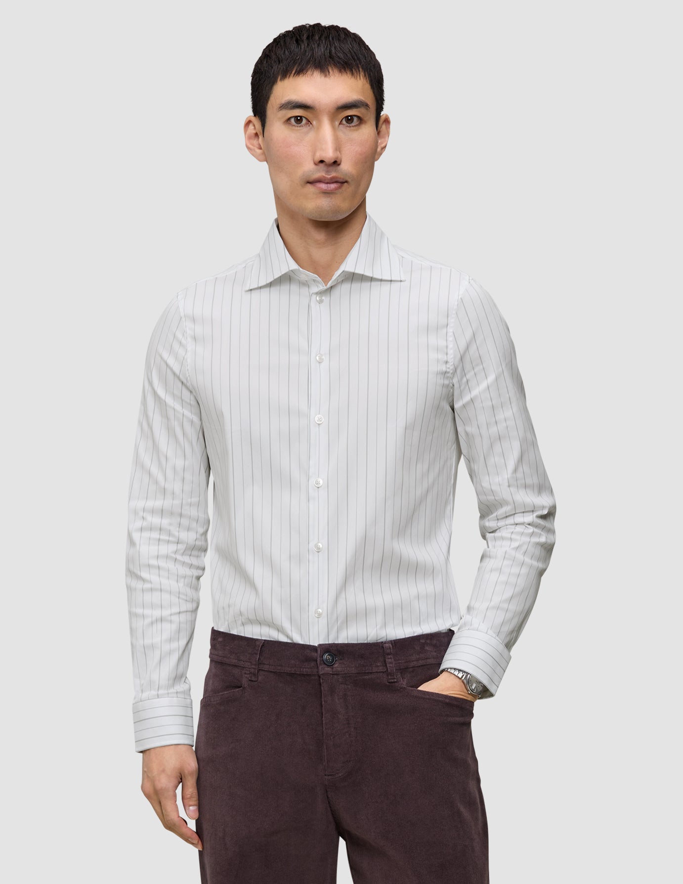 Man klädd i en slim fit-skjorta i ljusgrått med vertikala ränder och långa ärmar, modell Elevated Shirt Slim Light Grey Striped.