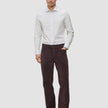 En man klädd i en ljusgrå randig skjorta av märket Elevated i modell Slim, mörka byxor och mörka loafers.