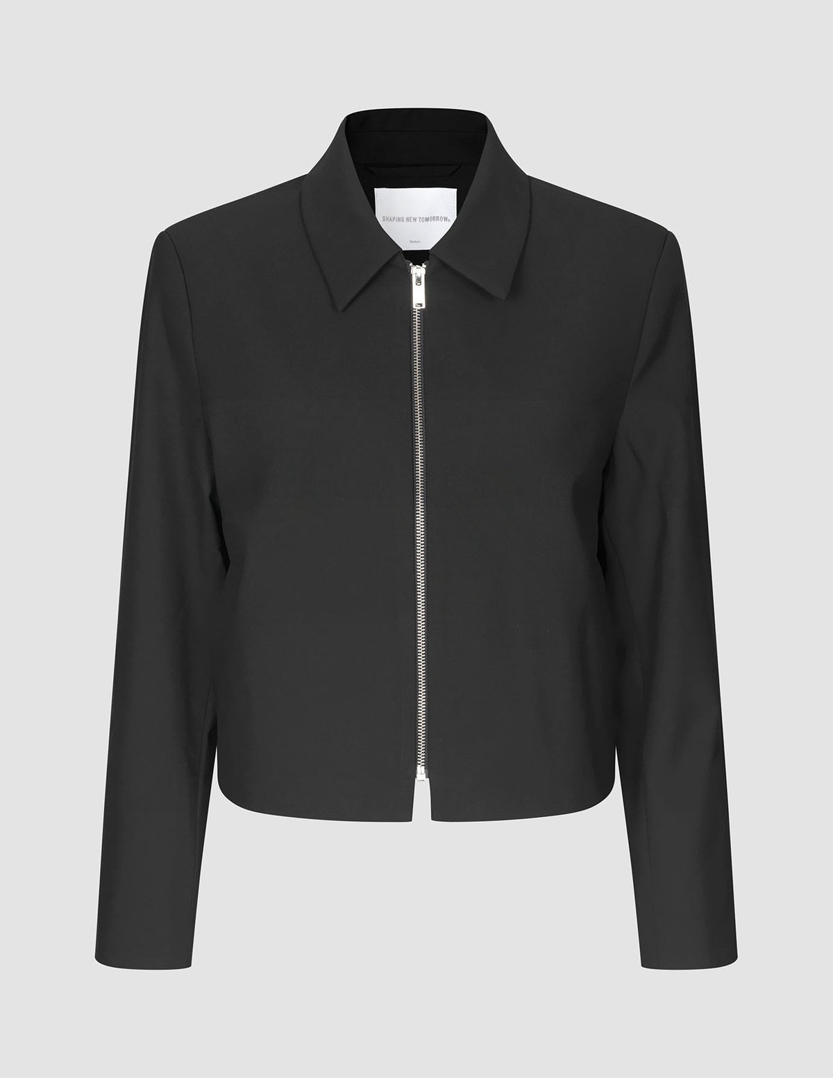 Essential Short Zip Jacket Black: en minimalistisk, kort svart jacka med en helsilverfärgad dragkedja framtill.