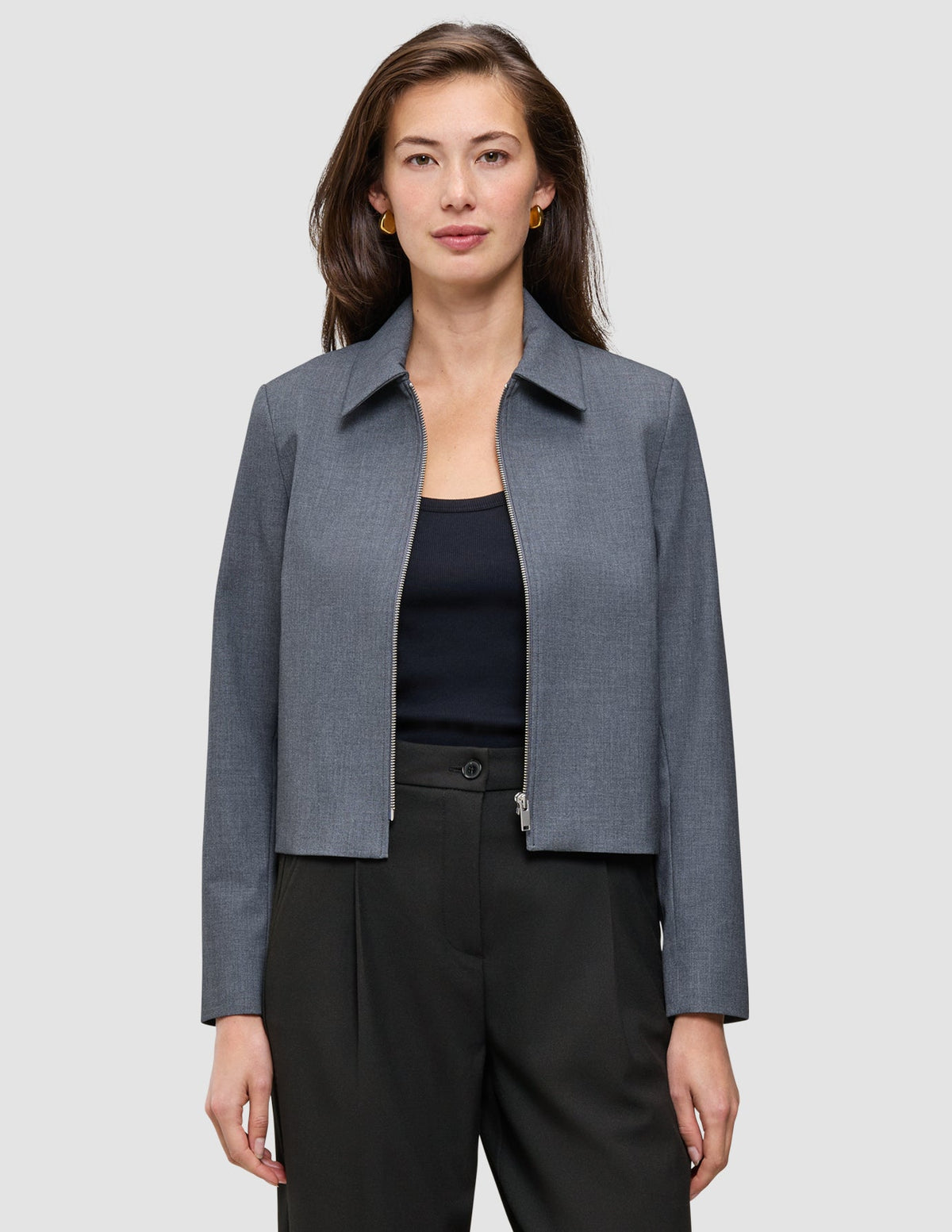 En kvinna som bär en mörkgrå Essential Short Zip Jacket i mörkgrå melange över en svart topp.