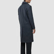 En man står i profil och bär en mörkgrå Maxi Wool Coat Dark Grey i kolgrått som når nedanför knäna.