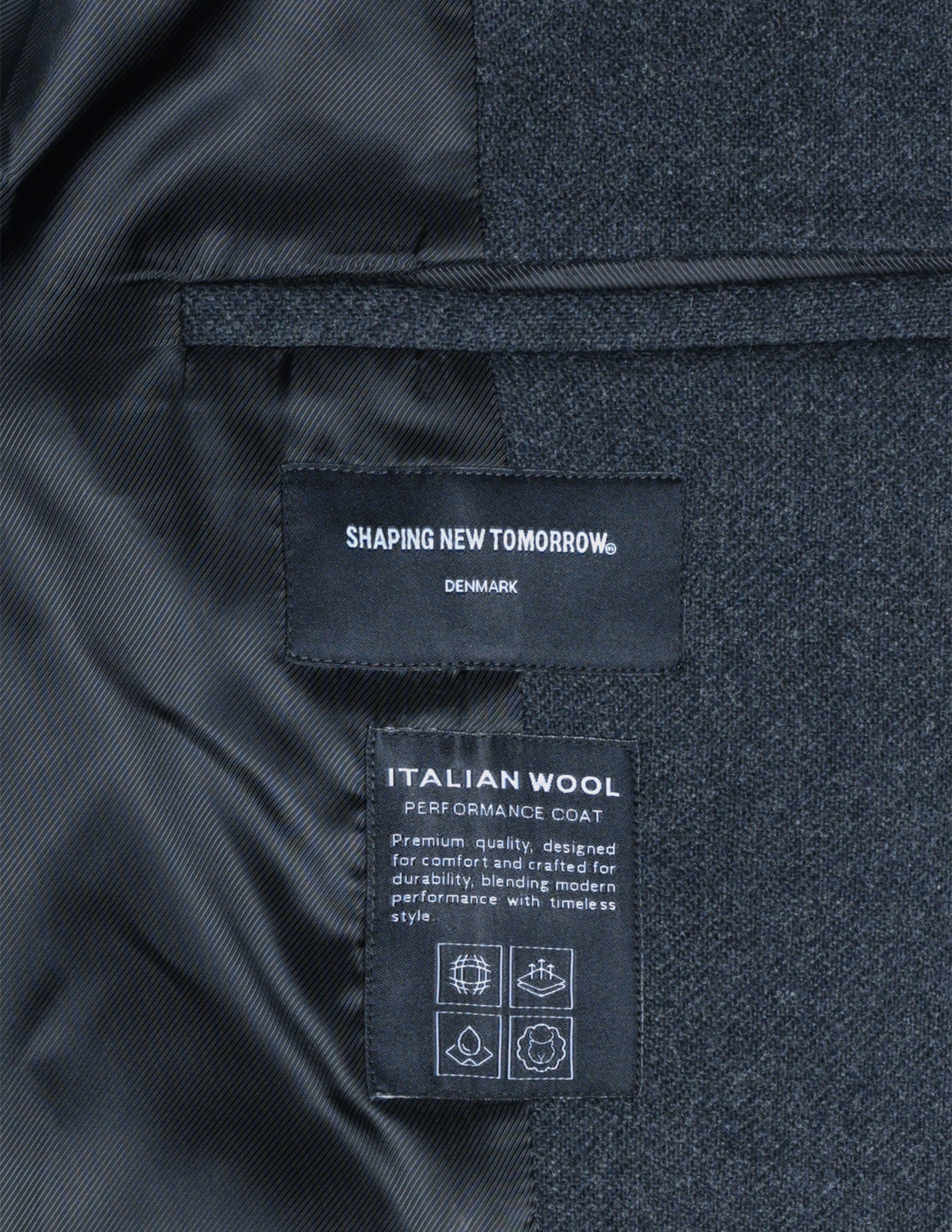 Två inre etiketter på en mörkgrå Maxi Wool Coat med uppgifter om märke, material och skötselråd.