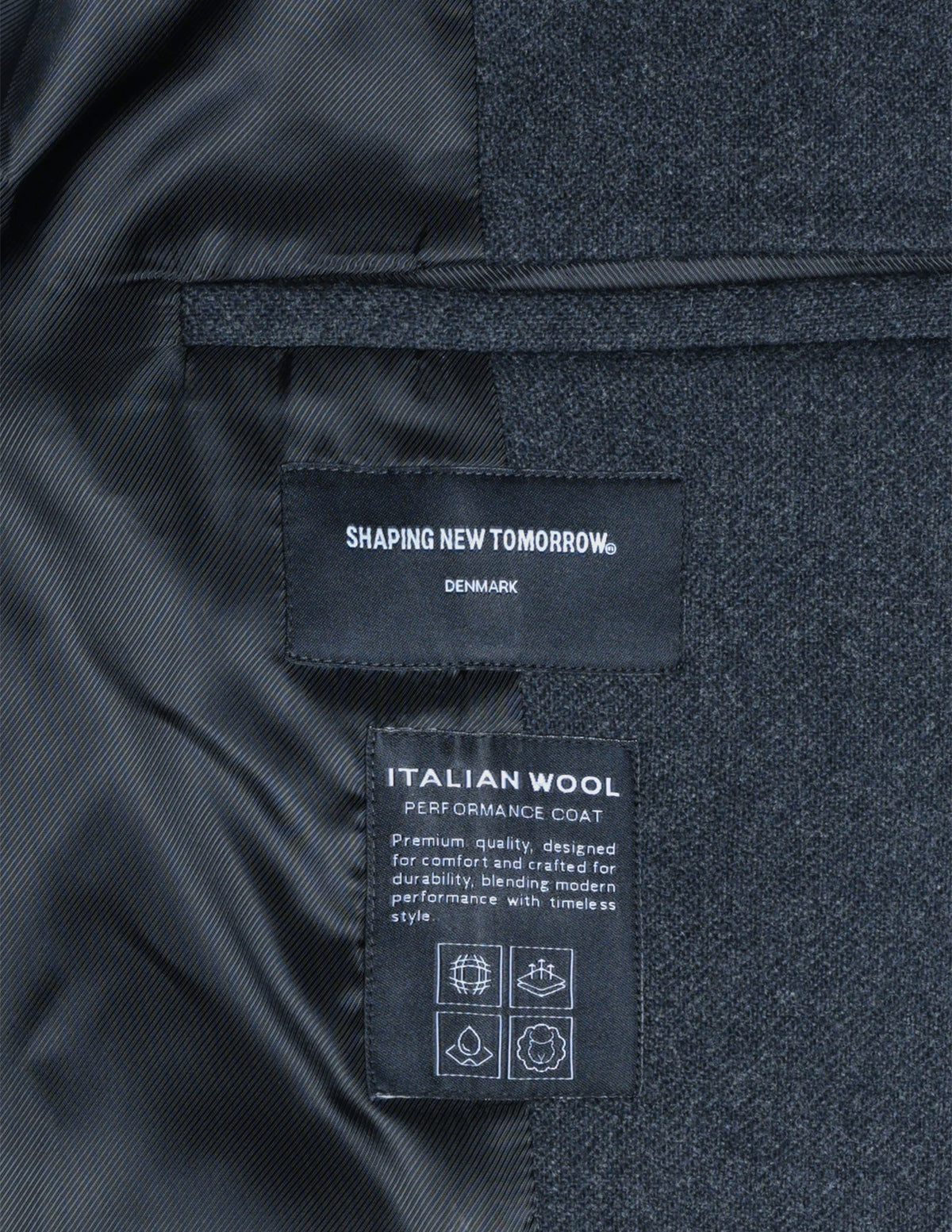 Två inre etiketter på en mörkgrå Maxi Wool Coat med uppgifter om märke, material och skötselråd.