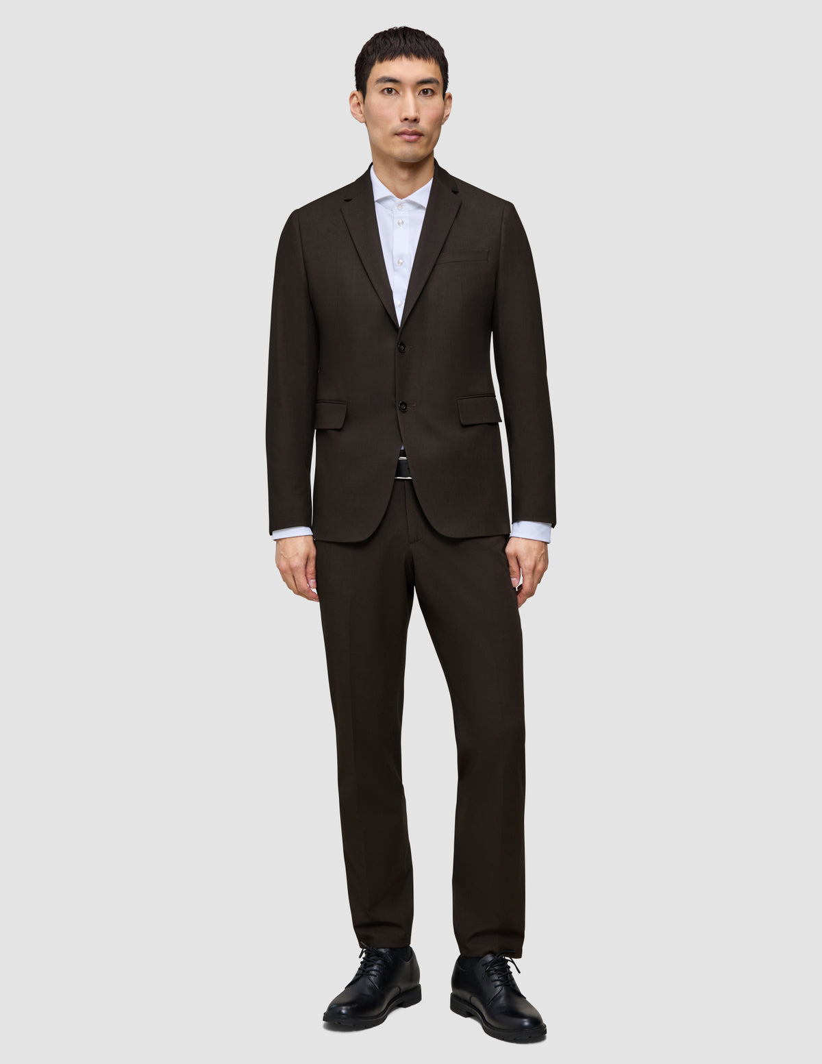 En man bär en Motion Blazer Regular i färgen Cognac över en vit skjorta med krage och svarta kostymskor.